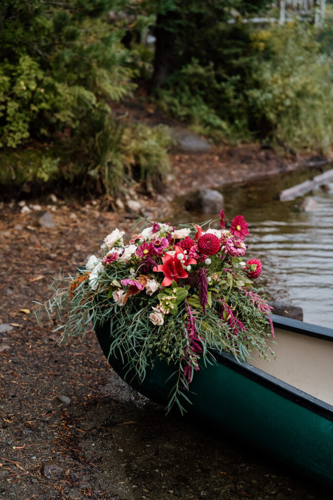 Canoe with stunning floral install rests on the beach during a Oregon Canoe Elopement at Trillium Lake.