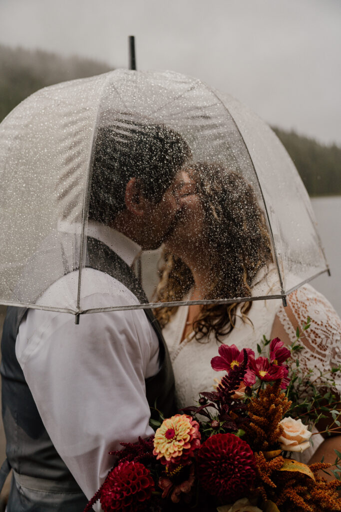 Bride and Groom kissing during their first dance in the rain during their Canoe Elopement at Trillium Lake in Oregon