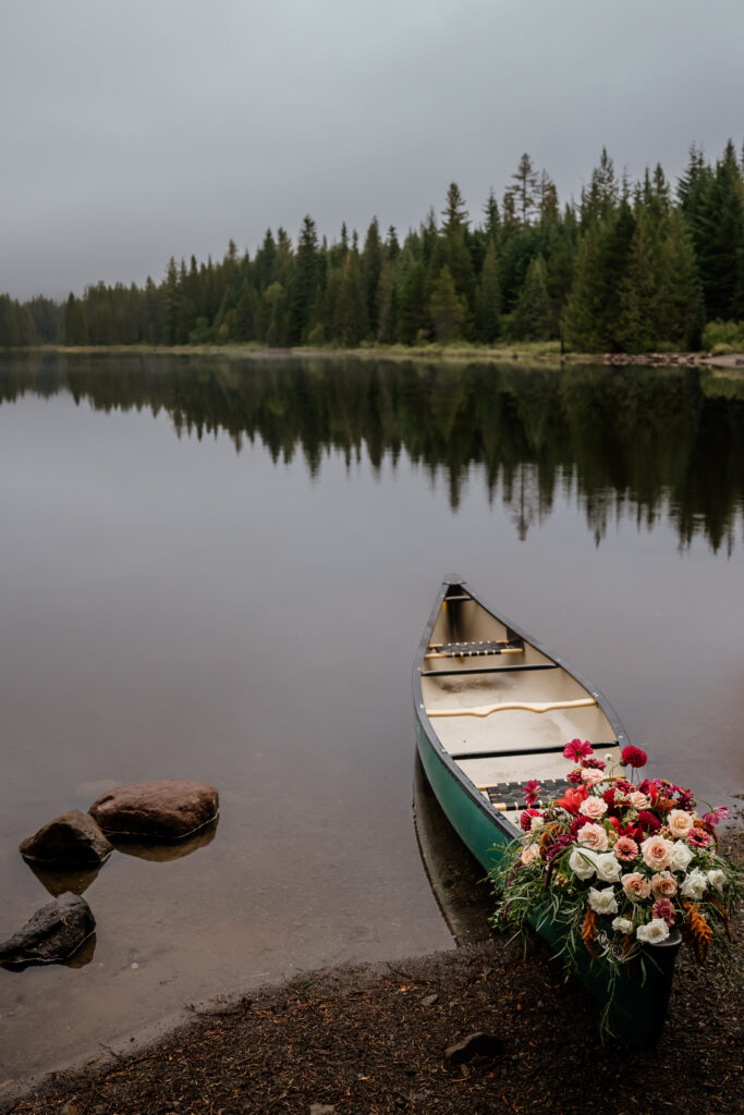 Canoe with a floral install rested against beach during a sunrise canoe elopement at Trillium Lake in Oregon