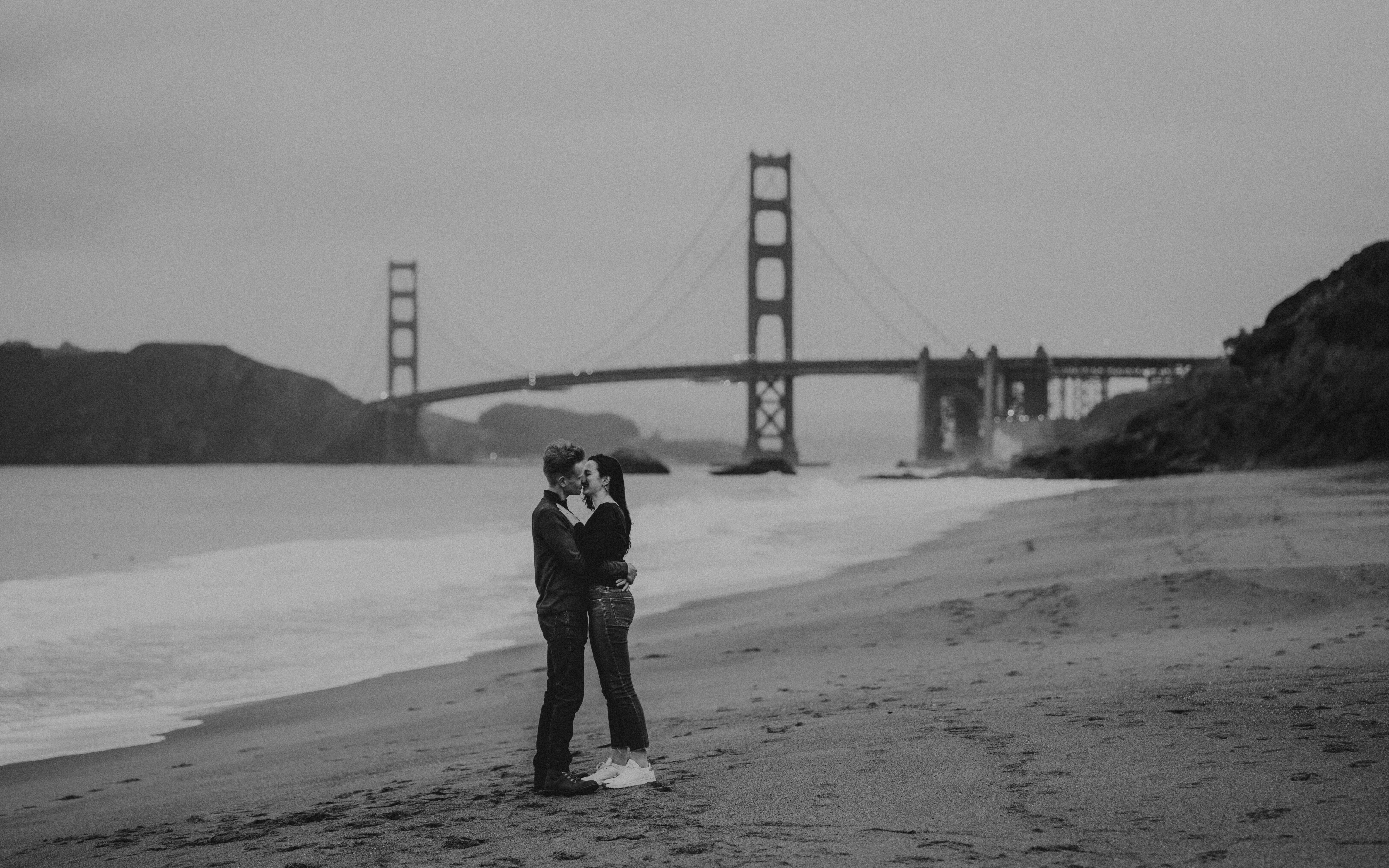 Couple posing in front of the Golden Gate Bridge in San Francisco for their engagement photos.