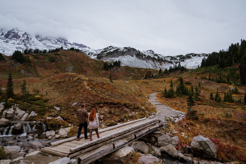 Couple walking over bridge at Myrtle Falls during their Fall Engagement shoot at Mount Rainier National Park