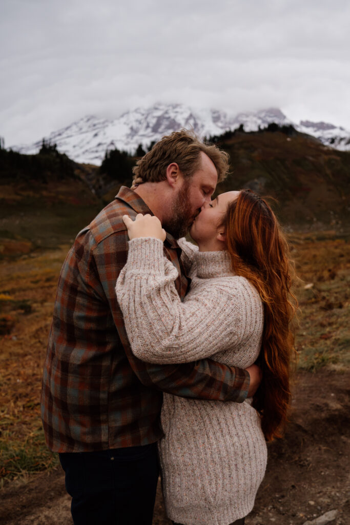 Couple kissing with the Fall colors of mount rainier in the background during their engagement session.