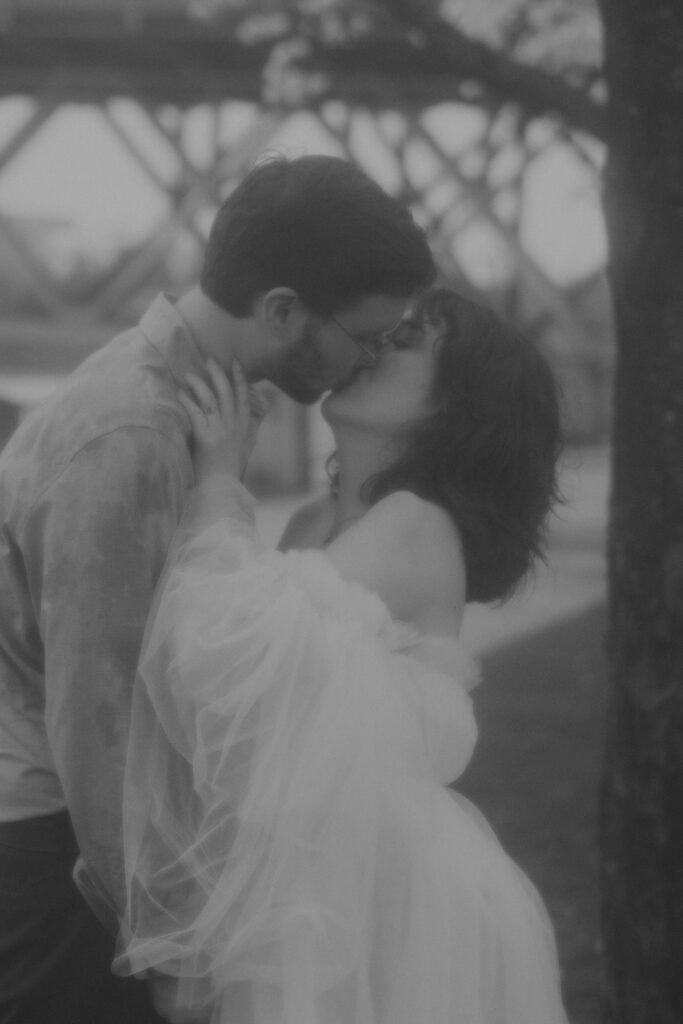 B+W photo of couple kissing in wedding attire at Tom McCall park in Portland during the Cherry Blossoms.