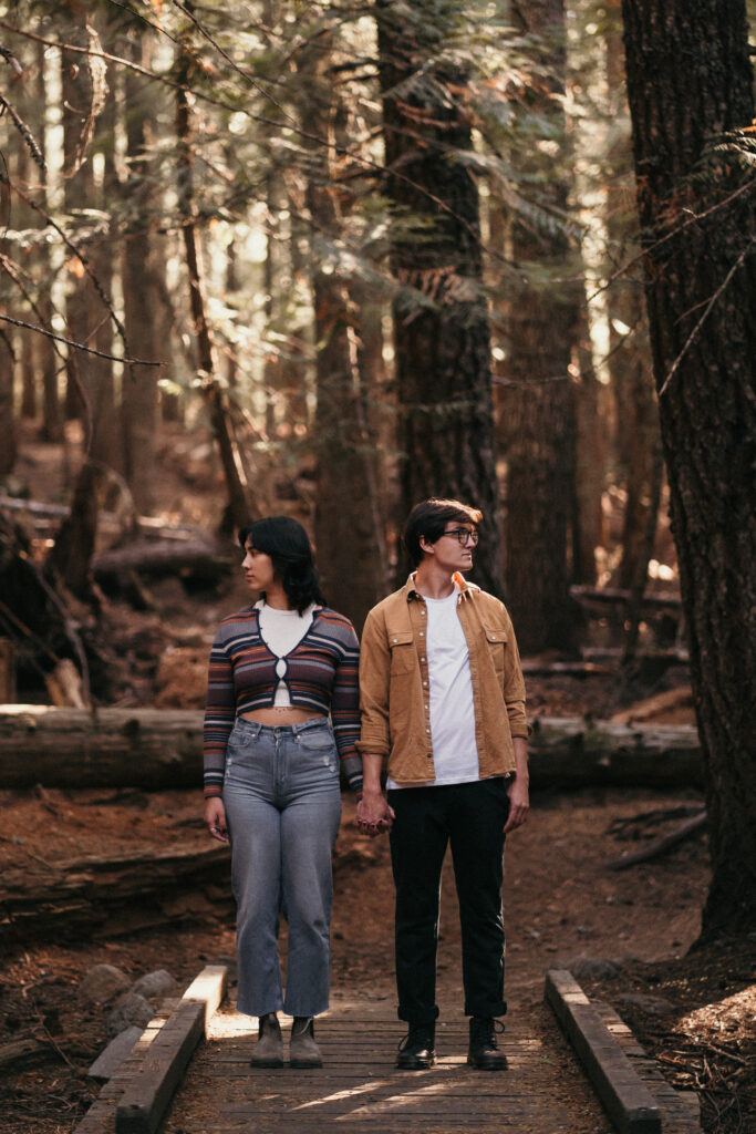 Couple holding hands and looking opposite directions in the forest near Trillium Lake.