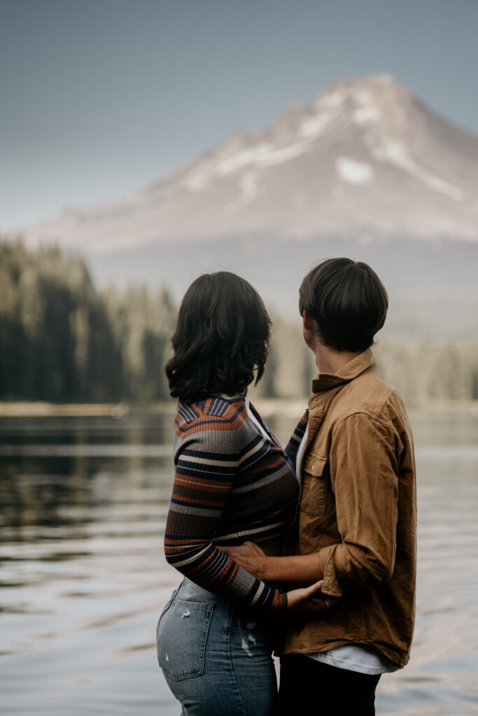 Couple looking at Trillium Lake and Mount Hood in the distance during their engagement session.