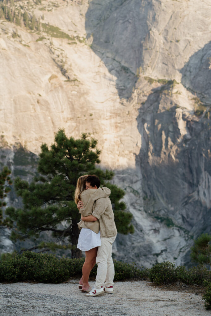 Couple hugging after their engagement with Half Dome in the background.