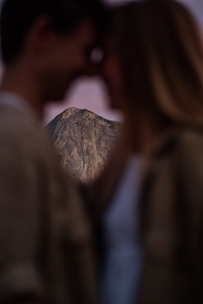 Photo of Half dome from between a couple standing nose to nose from their Yosemite National Park proposal photos.