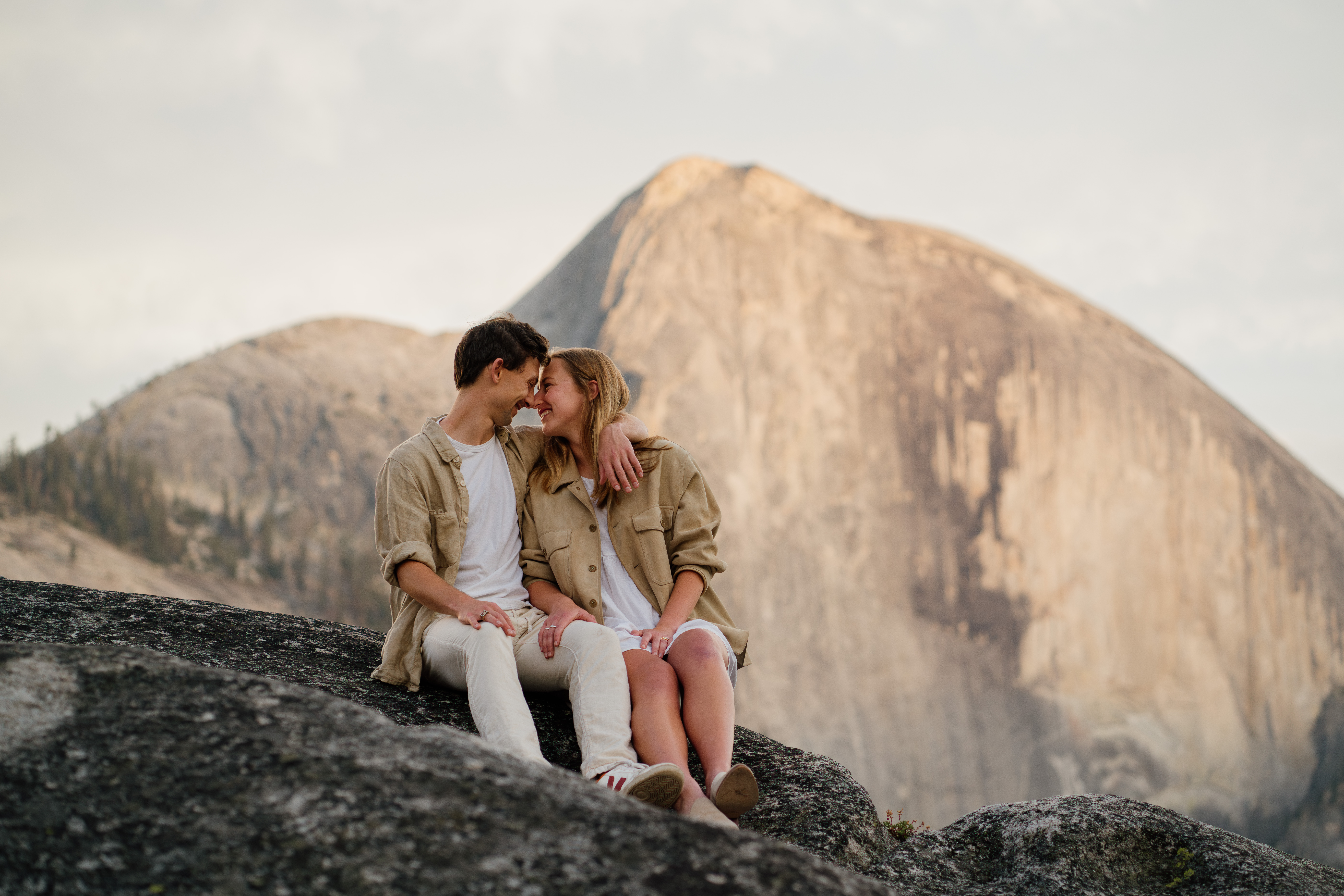 Couple sitting and looking at eachother during their yosemite engagements photos with half dome in the background.