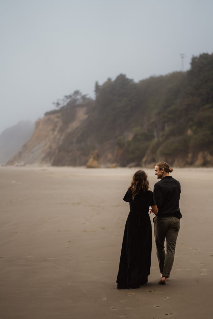 Couple walking away from photographer during their Cannon Beach, Oregon engagement session.