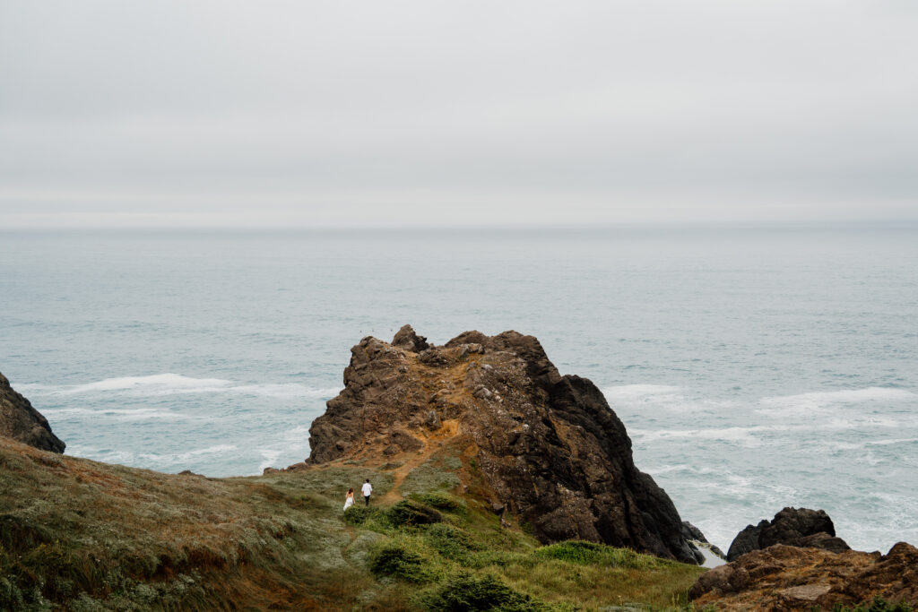 Couple in elopement attire hiking along the Oregon Coast during their Oregon Adventure Elopement.