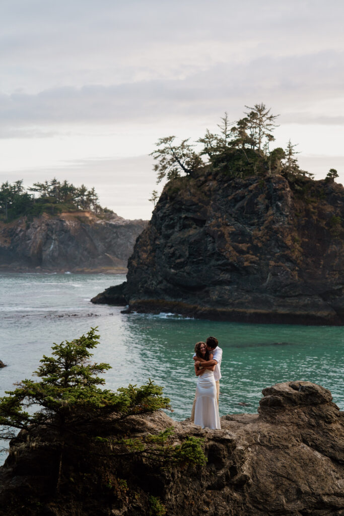 Groom hugging bride from behind and kissing her cheek during their Samuel H Boardman adventure elopement. 