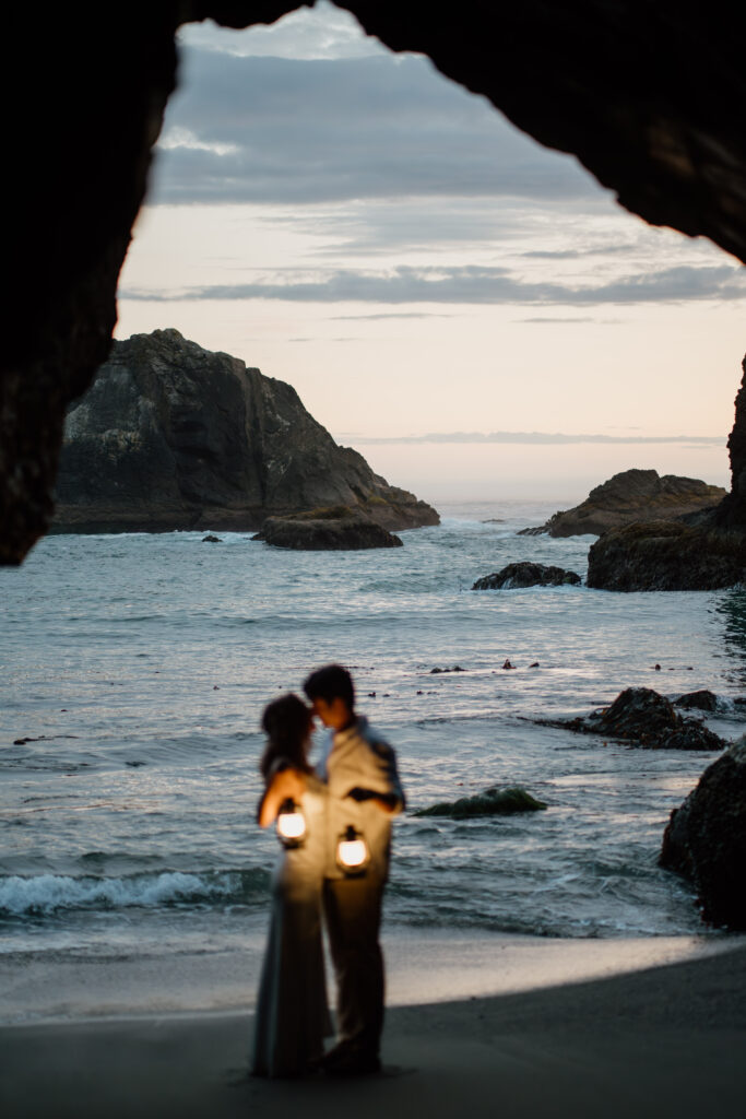 Couple holding lanterns as it begins to get dark on their Oregon Coast elopement.