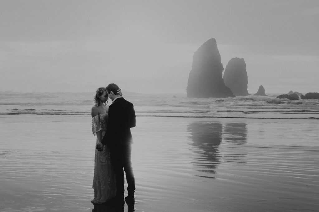 Bride and groom standing forehead to forehead with the Iconic Haystack rock in the background during their elopement.