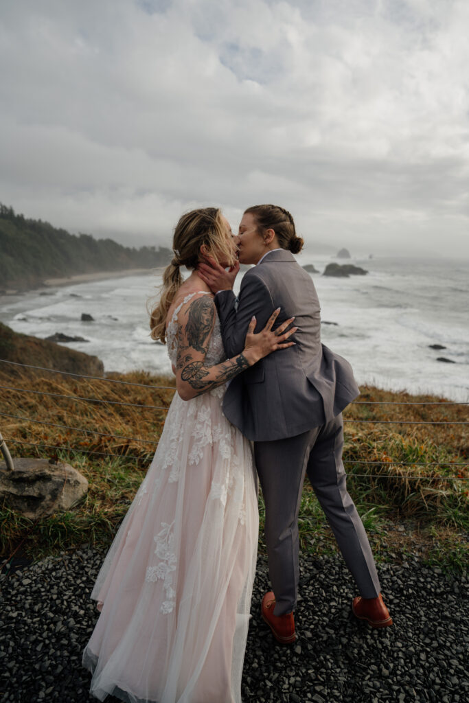 Couple kissing with rocky Oregon Coast and the iconic Haystack Rock in background.