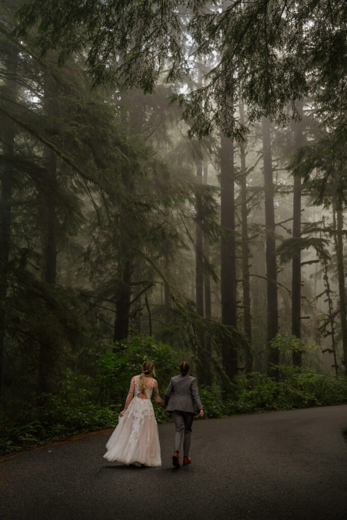 Couple running up road surrounded by the foggy forest at Ecola State Park during their Cannon Beach Elopement.