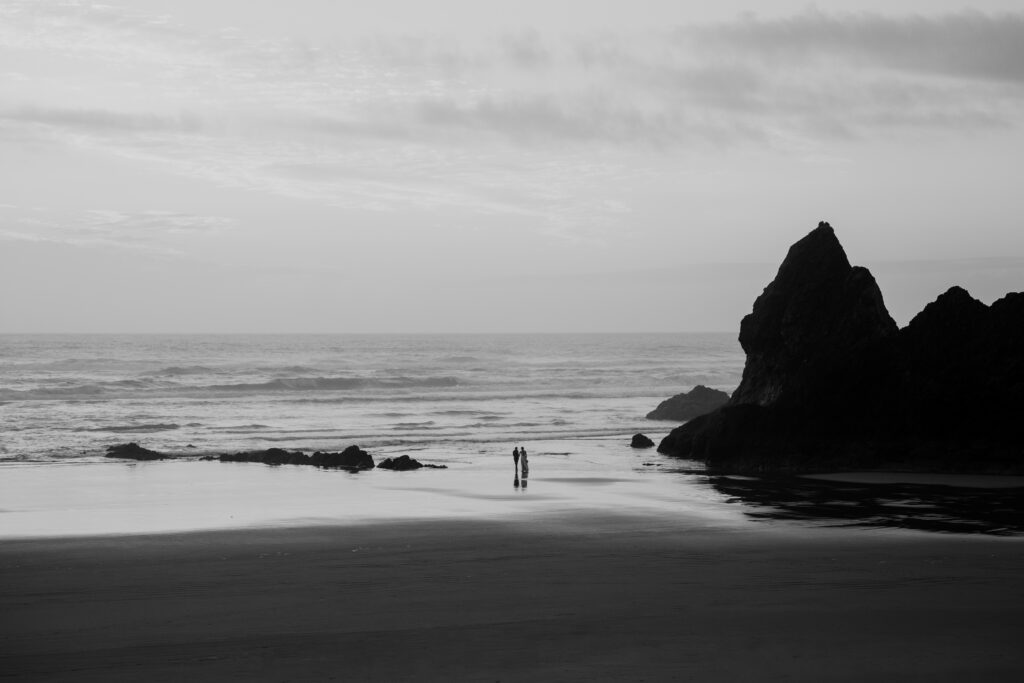 Landscape shot with small brides in the distance exploring Arcadia Beach on their Oregon Coast Elopement Day.