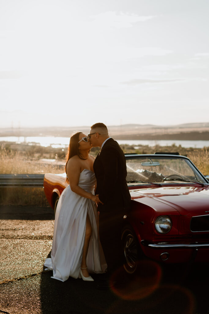 Couple kissing in front of a classic ford mustang in formal attire with the Columbia River Gorge in the background.
