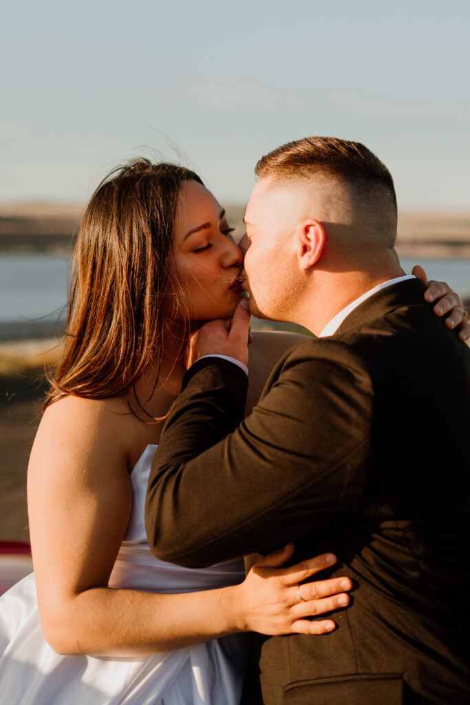 Couple kissing during golden hour with the Columbia River Gorge in the background during their Columbia River Gorge Vintage Car engagement photo session.