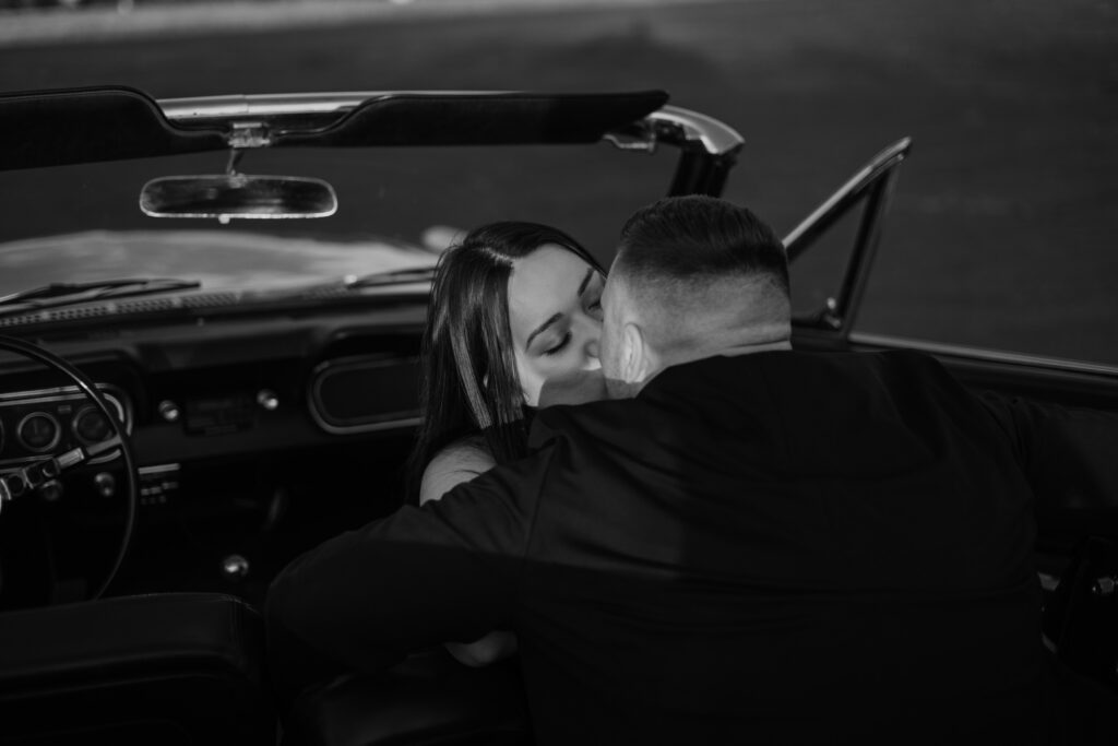 Woman kissing man in Vintage Ford Mustang during their Columbia River Gorge Vintage Car Engagement Photos.