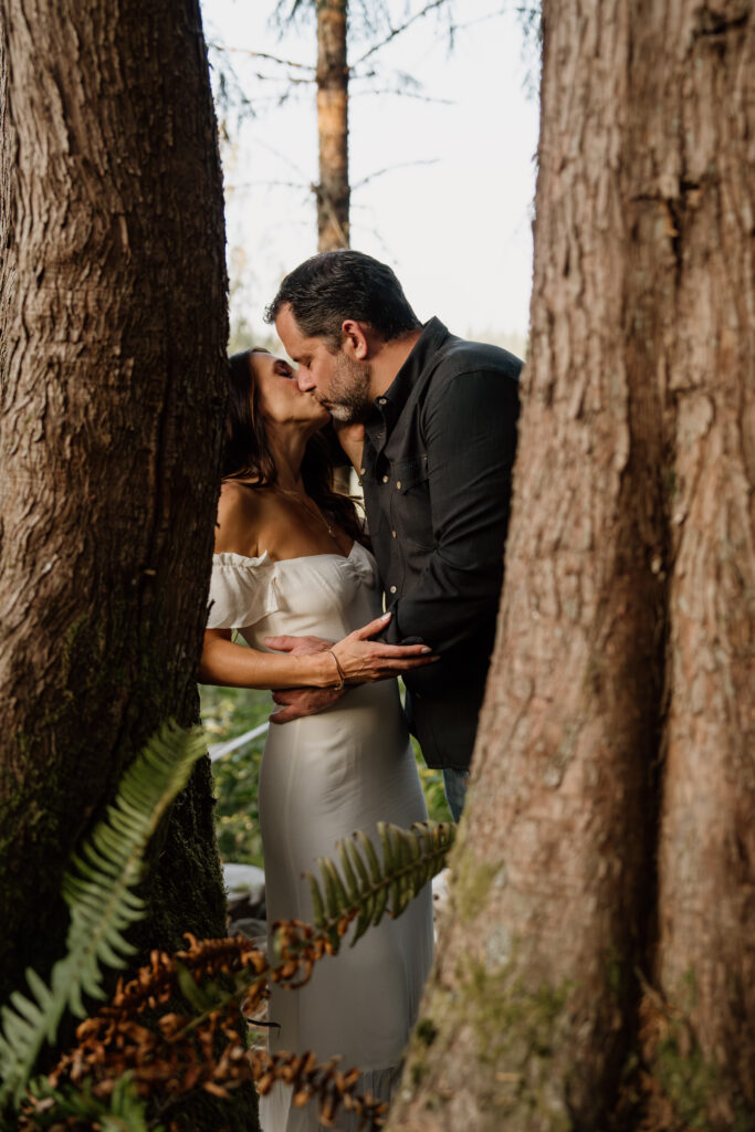 Couple kissing between tree trunks during their Seattle engagement photos.