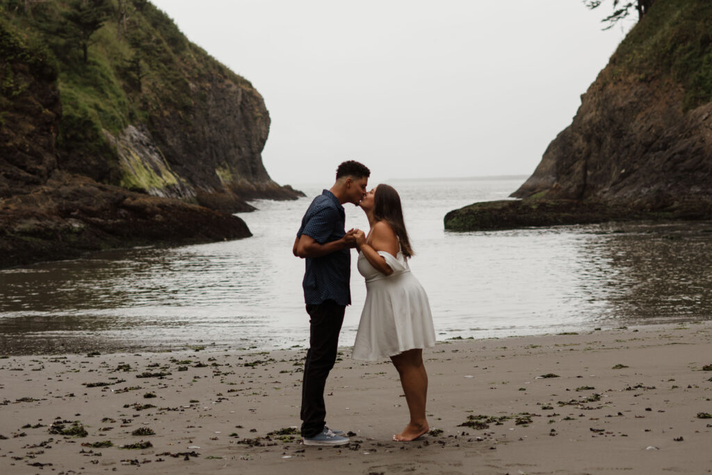 Couple holding hands and leaning in to kiss during their Washington Coast Engagement Photos.