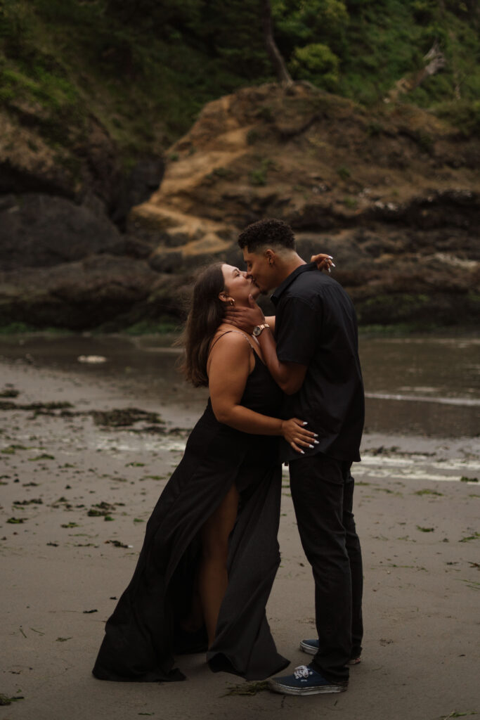 Couple standing and kissing with the stunning Washington Coast in the background.