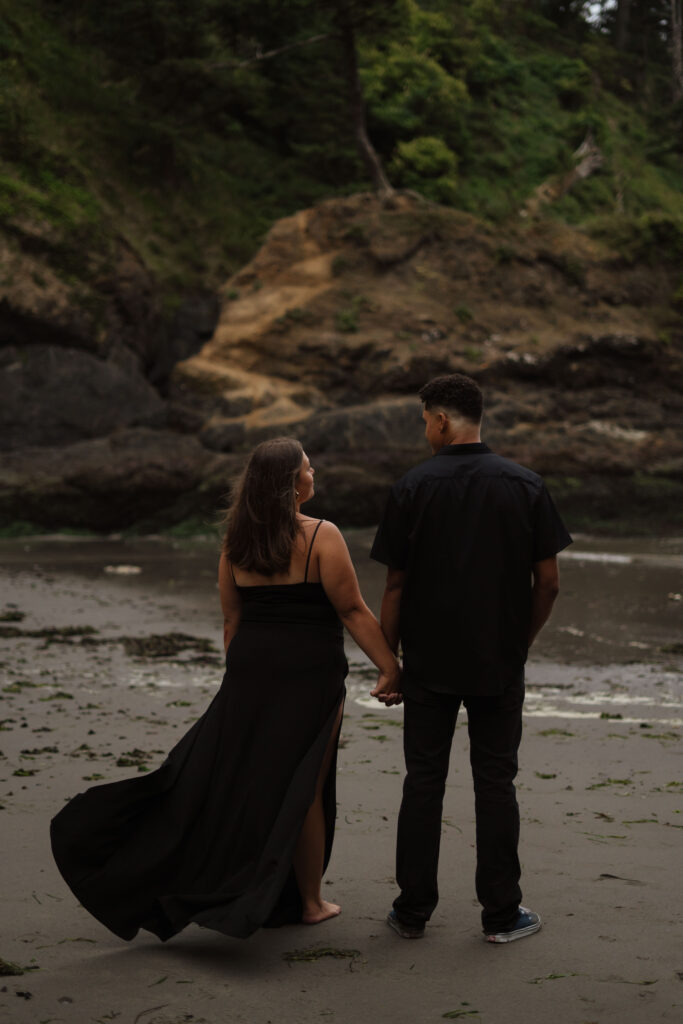 Couple holding hands and looking at each other looking out at the Washington Coast.