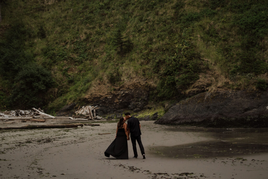 Couple walking away from the camera and leaning in to kiss during their Washington Coast engagement session.