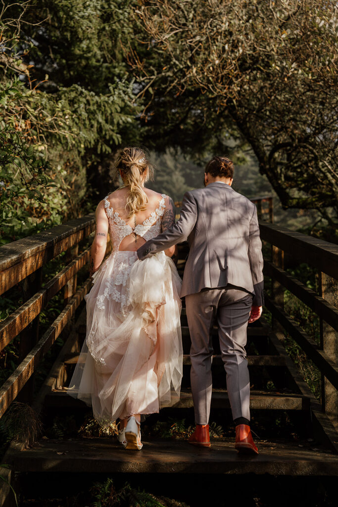 Brides walking over a wooden bridge to their Oregon beach elopement ceremony