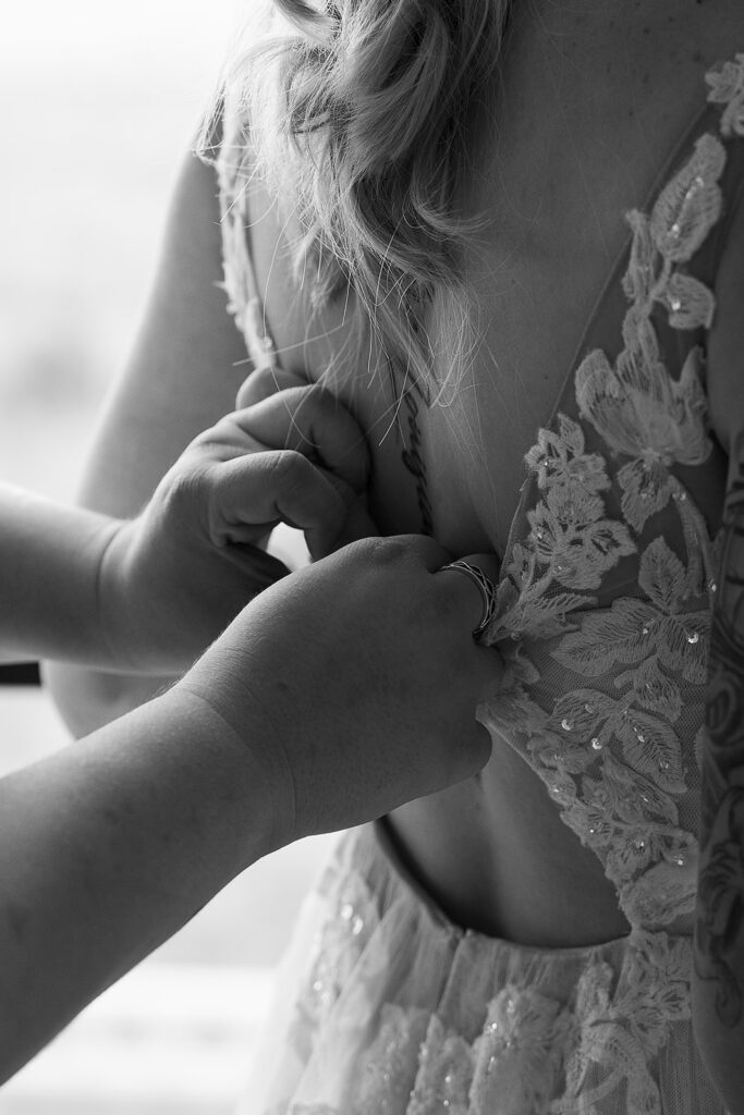 friend helps bride with her dress