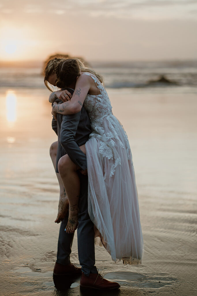 Couple hugs as the ocean comes up to shore during golden hour