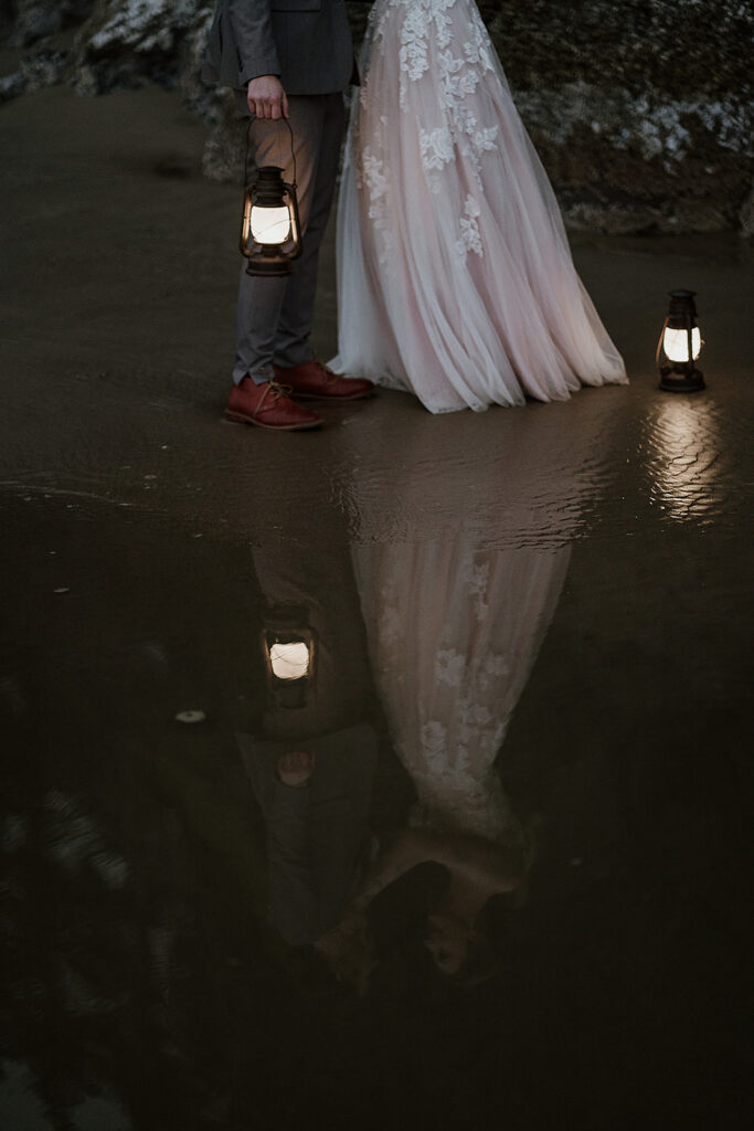 two brides with lanterns reflecting in the ocean water