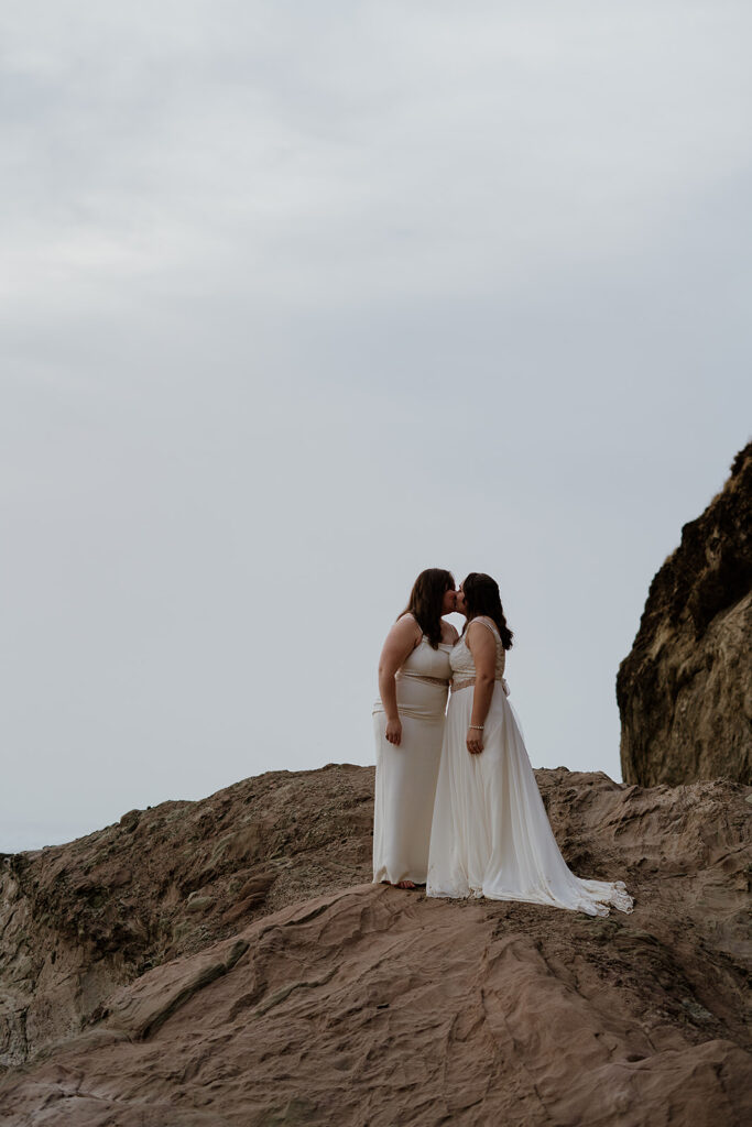 Couple kisses on some large rocks along the Arcadia beach shore