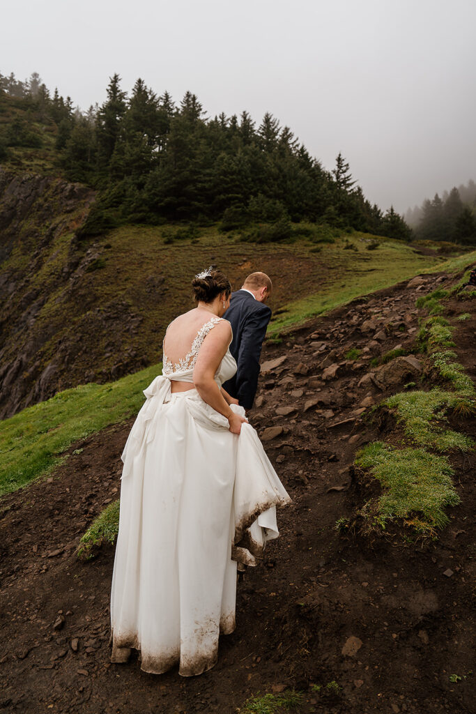 Bride hikes up a trail with her dirty wedding dress