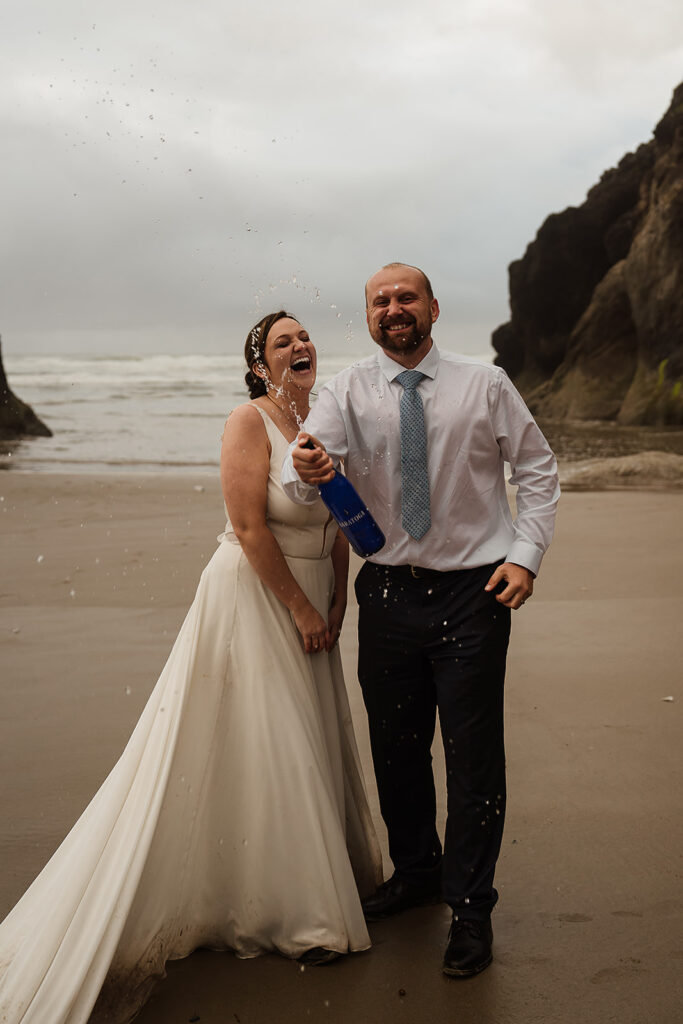 Bride and Groom pop a bottle of champagne on the Oregon Coast beach