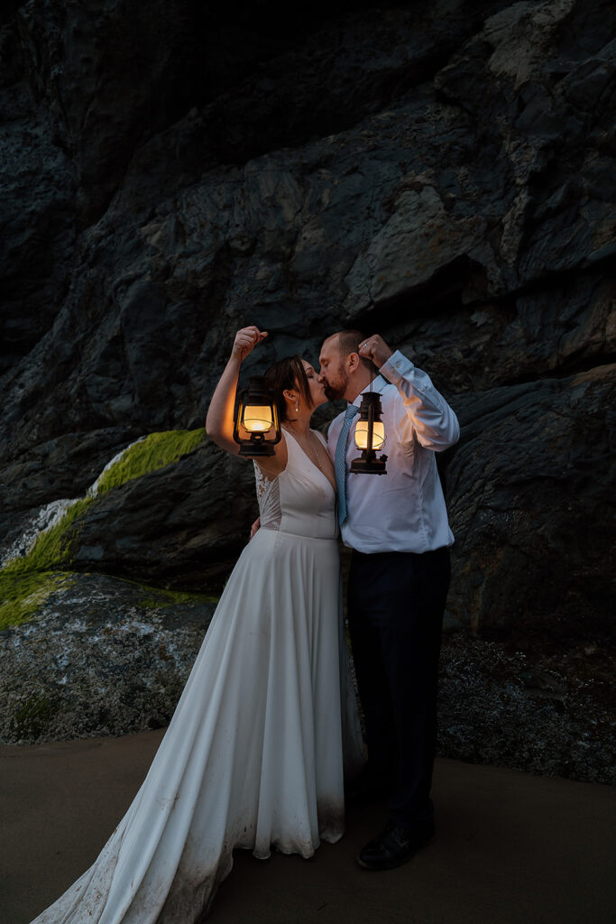 Bride and groom hold up lanterns by a rocky cliff