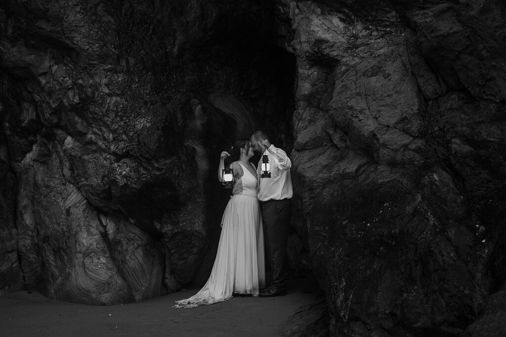 Bride and groom hold up lanterns by a rocky cliff