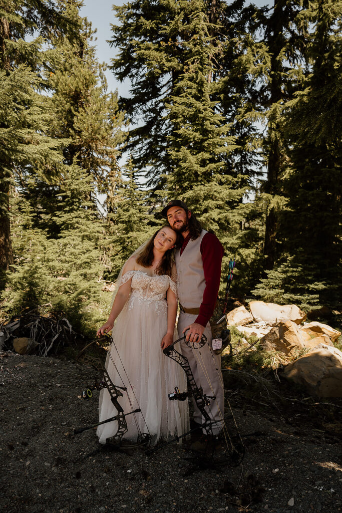 Bride and groom stand closely with their archery gear by their sides