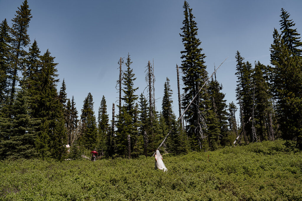 Couple walking through some tall greenery into the forest during their Oregon adventure elopement