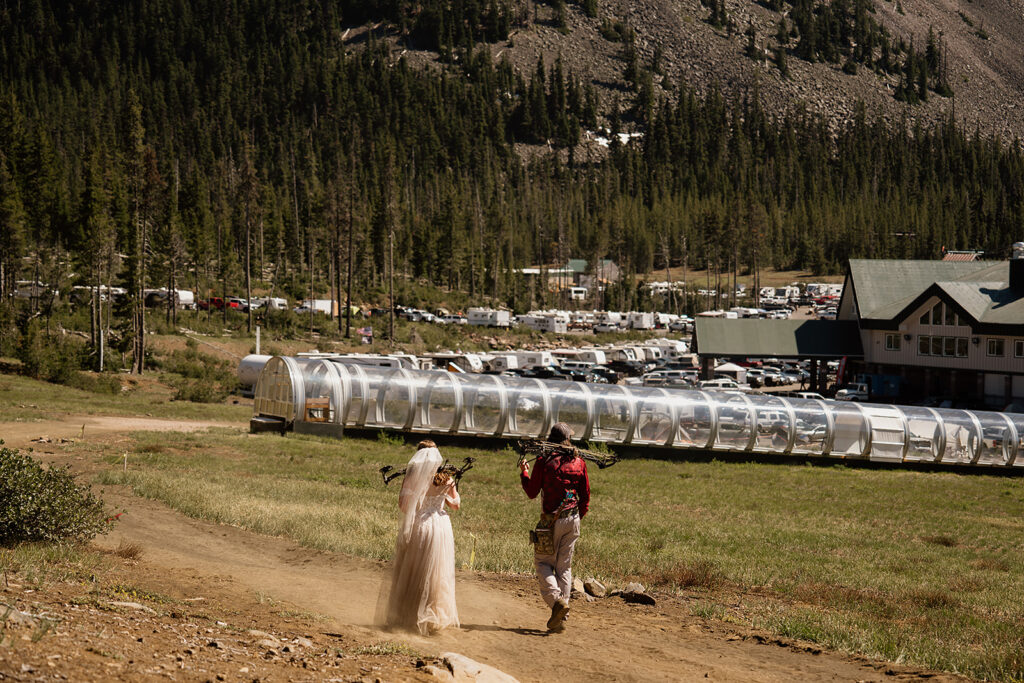 Bride and groom hike back down the mountain after they finish an adventurous archery course