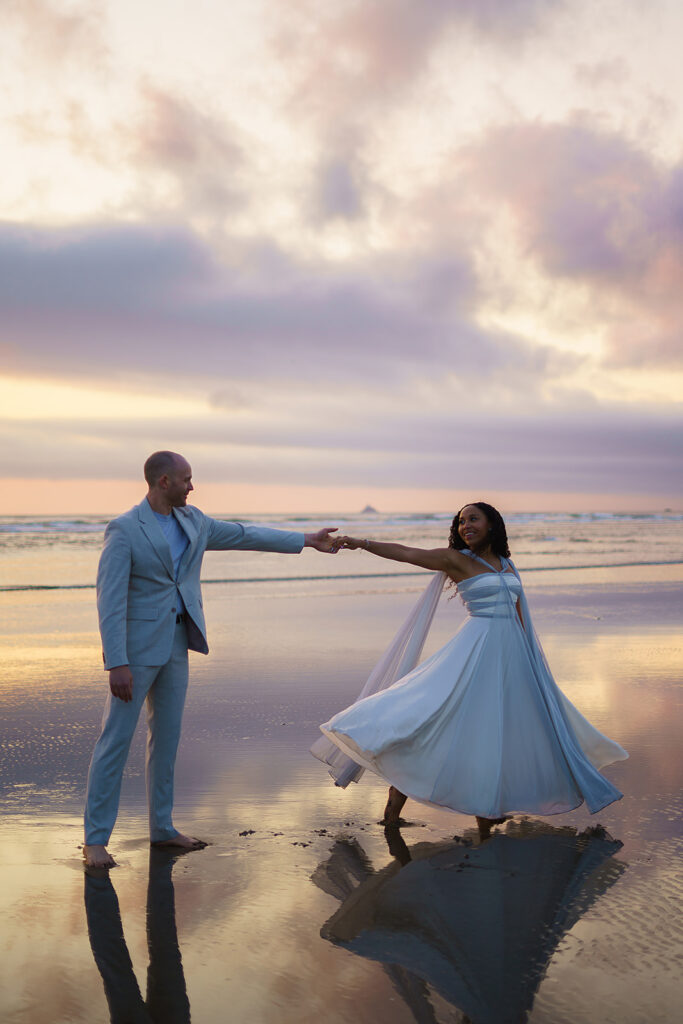 Cotton candy skies surround bride and groom as they dance on Cannon Beach during their post-nuptial shoot