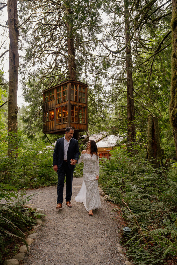 Couple walks a gravel path with Treehouse Point in the backdrop