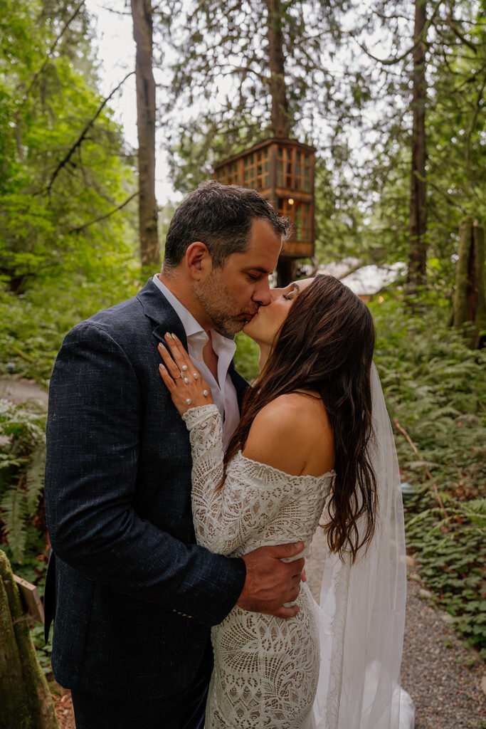 Couple kisses with Treehouse Point in the backdrop