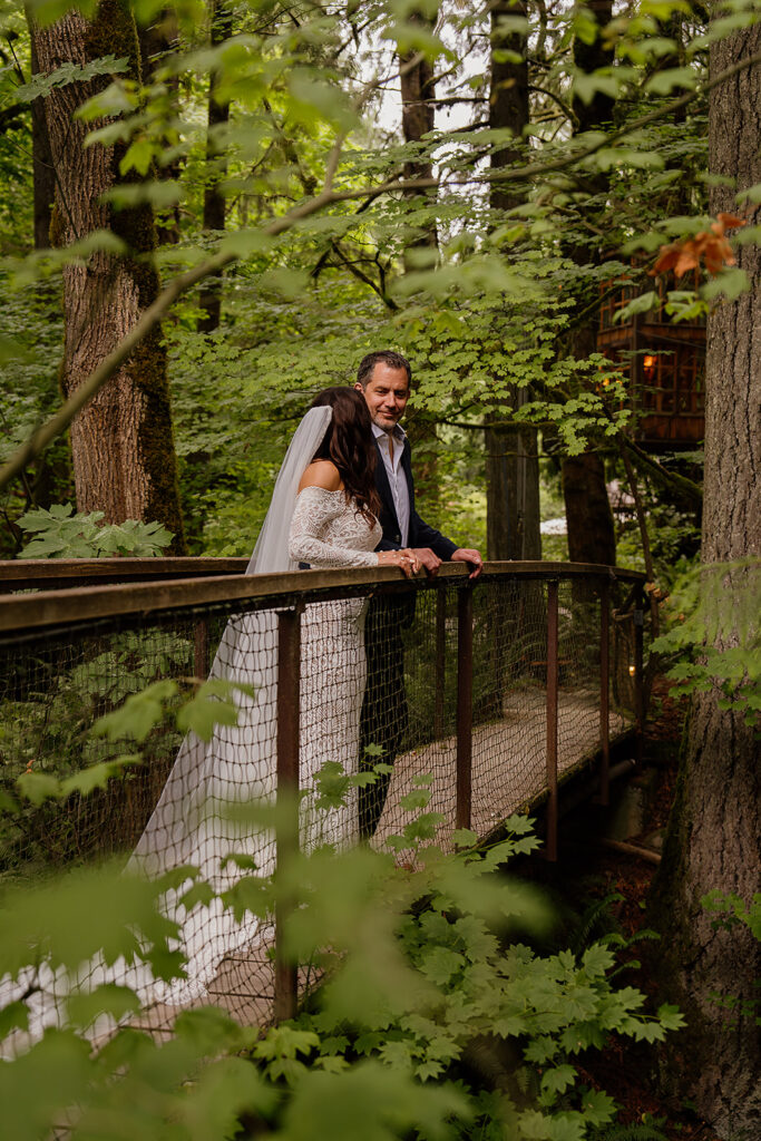 Couple standing on a wooden bridge surrounded by green foliage