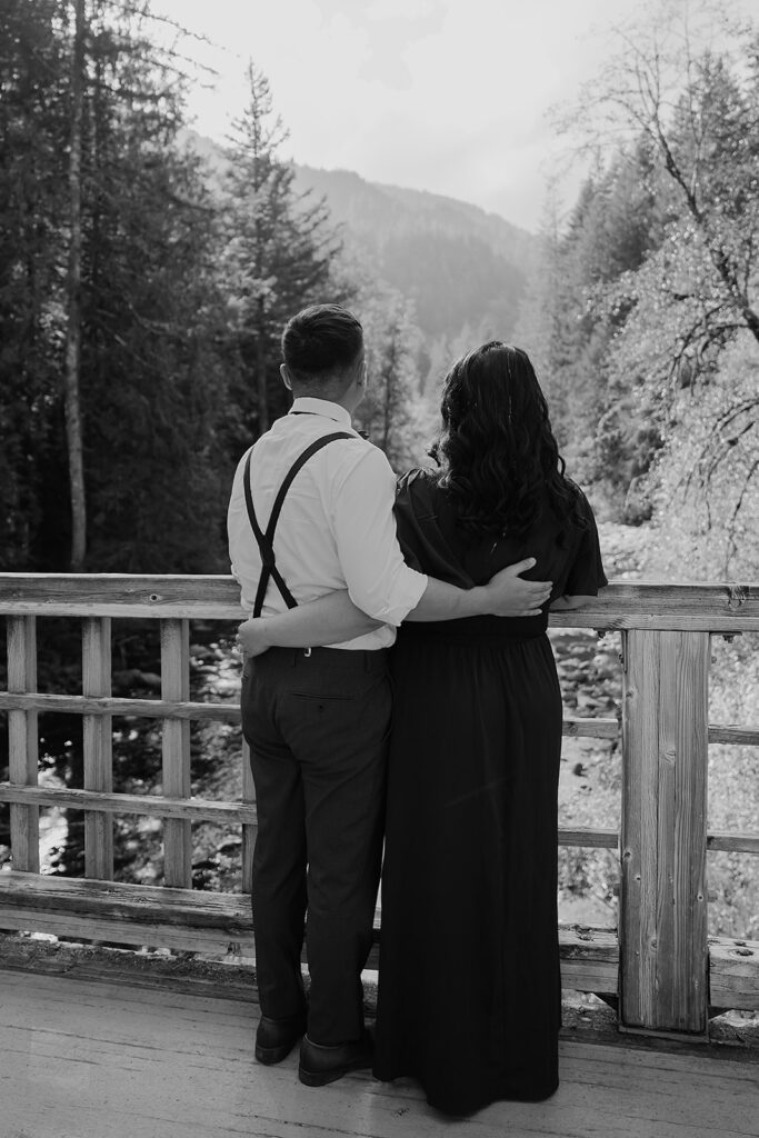 Couple stands on a wooden bridge for their outdoor photoshoot in Mount Hood National Forest