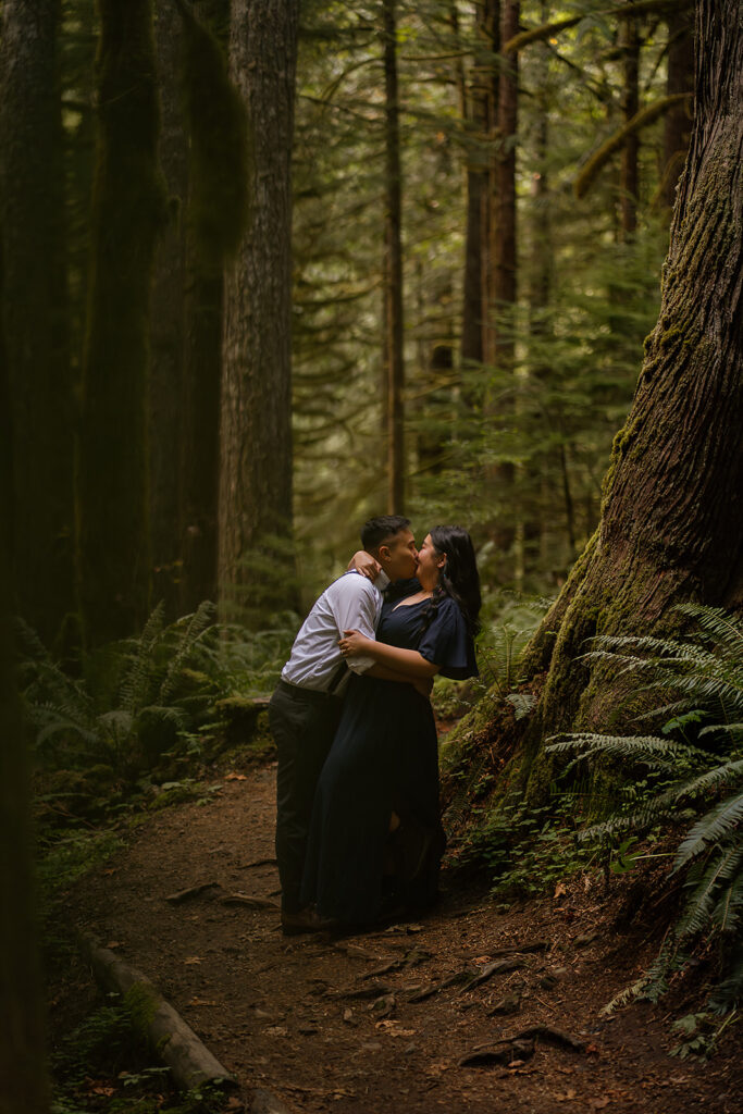 Couple kissing under towering redwoods at Wildwood Recreation Site for their outdoor photoshoot