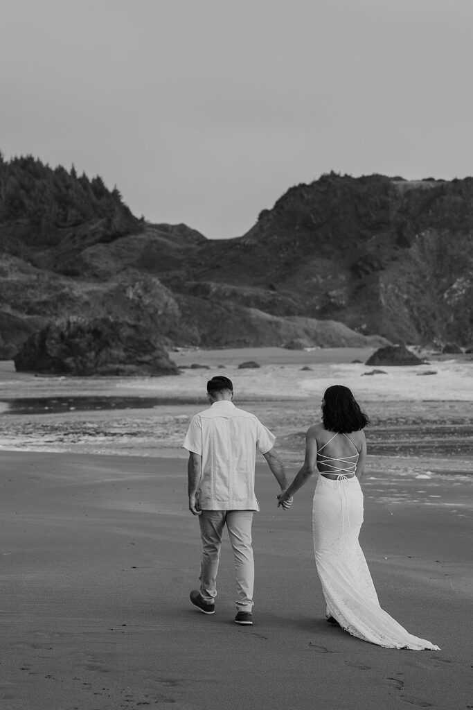 Bride and groom walk along the Oregon coastline after their micro wedding ceremony