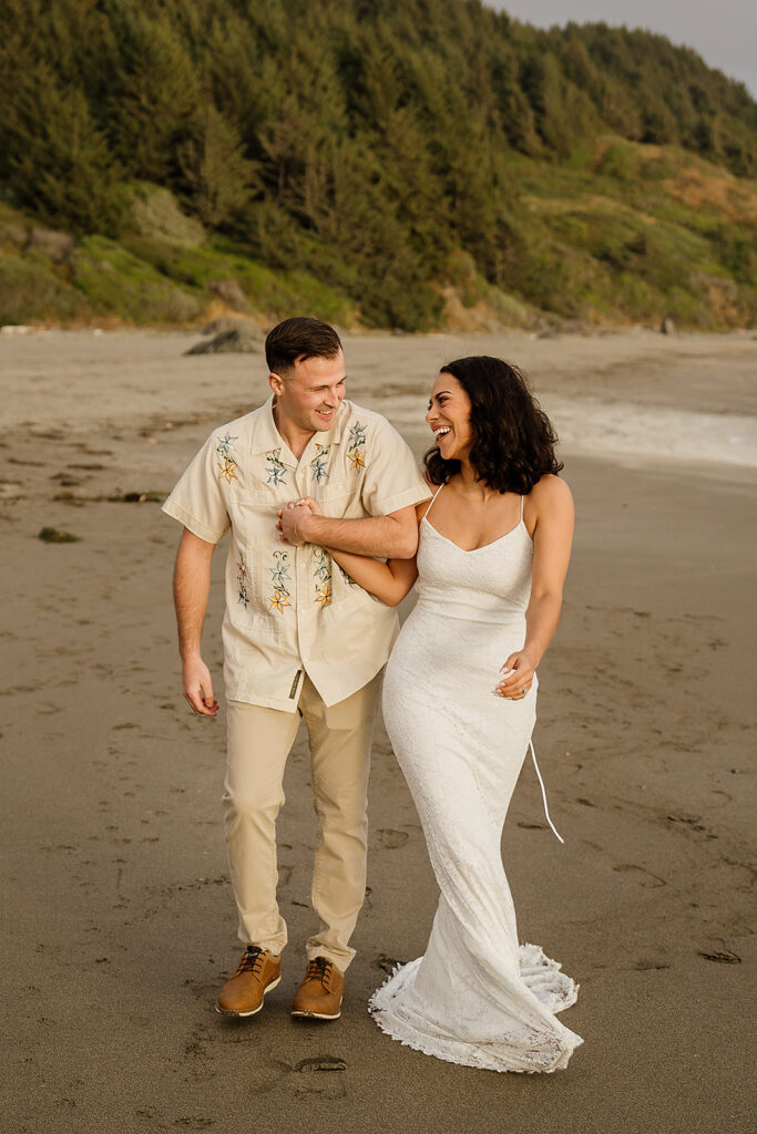 Bride and groom walk along the Oregon coastline after their micro wedding ceremony