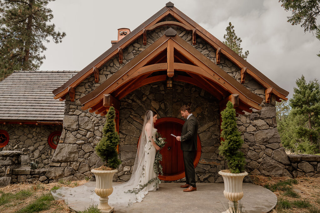 Bride and groom read their private vows in front of a stone cottage in the Columbia River Gorge