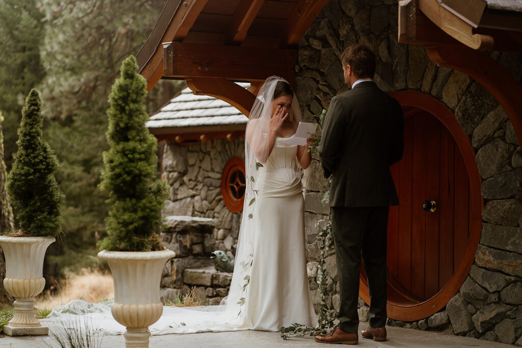 Bride and groom read their private vows in front of a stone cottage in the Columbia River Gorge